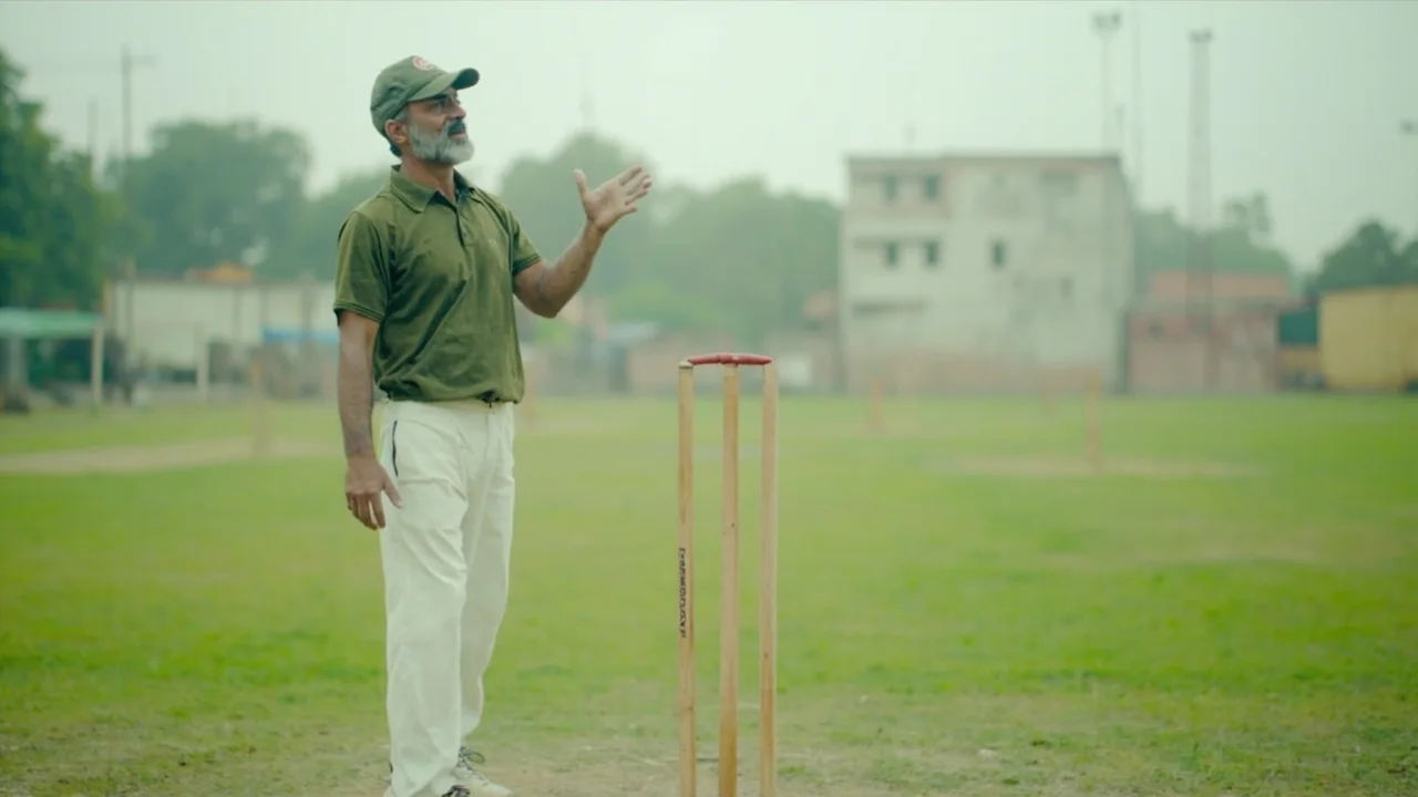 A young player holding a cricket bat across his shoulders during a daytime nets session